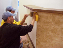 Workers apply Adobe Mirastain II to accent the sides of the front counter.