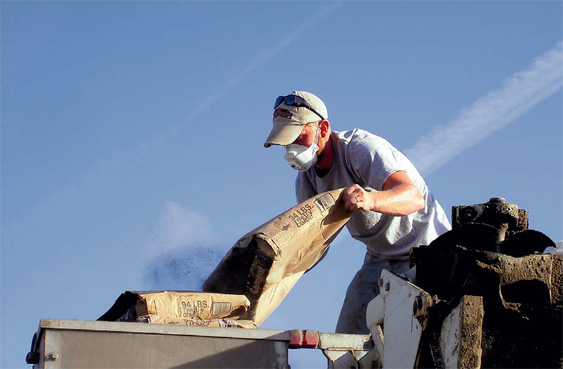 Contractor with mask, mixing concrete.