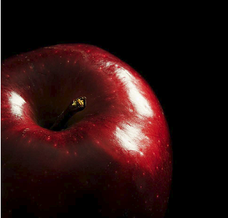 The apple is red, but because the surface is glossy, the light source is visible as a white highlight.