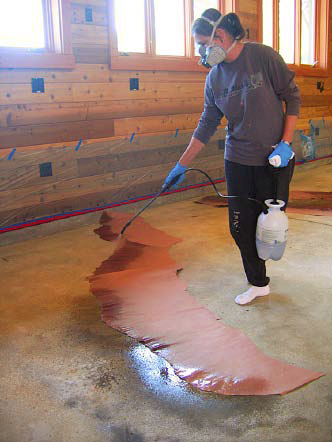 Concretist Brenda Walz uses an all-plastic, pump-up garden sprayer at a Martinez, Calif., home to apply stain along a stratalike torn paper edge and over scattered Ironite granules.