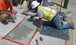 Construction worker replacing failed stamped overlay.