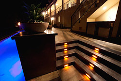 The steps are illuminated with inset lighting that features yellow, white and orange swirled glass with a copper frame, adding to the overall artistic feel of the area. The golden-yellow lights were designed to pop off of the grey concrete.