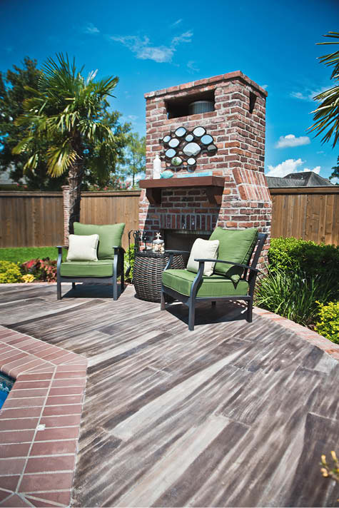Outdoor fireplace with a pool deck of faux wood planks.