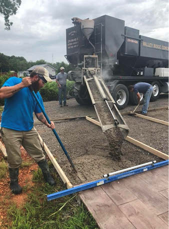 A crew member places colored concrete from a mobile mixer during a training demonstration.