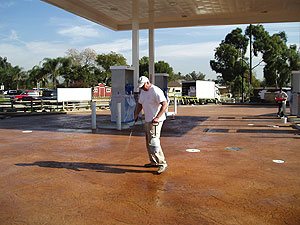 Richard Smith cleaning a large stained concrete gas station parking lot after his job was finished.