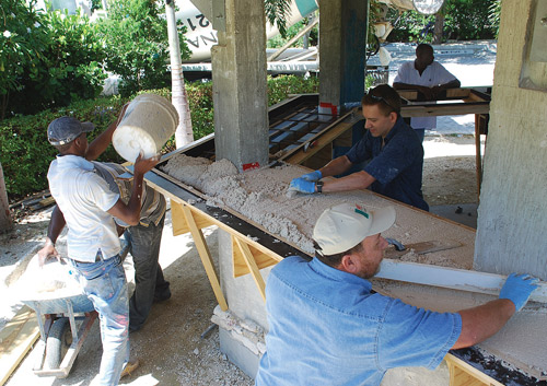 Jeff Girard (in the dark blue shirt) helps a crew place and screed concrete for a bar top in the Cayman Islands. Photos courtesy of The Concrete Countertop Institute