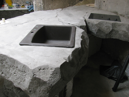Two sinks have been placed into a concrete countertop of sorts that is carved and custom made during a workshop.