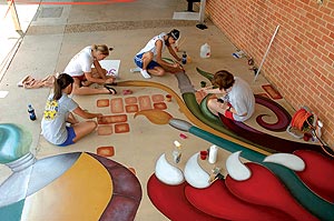 Students Apply Color to a public art project on a concrete sidewalk.