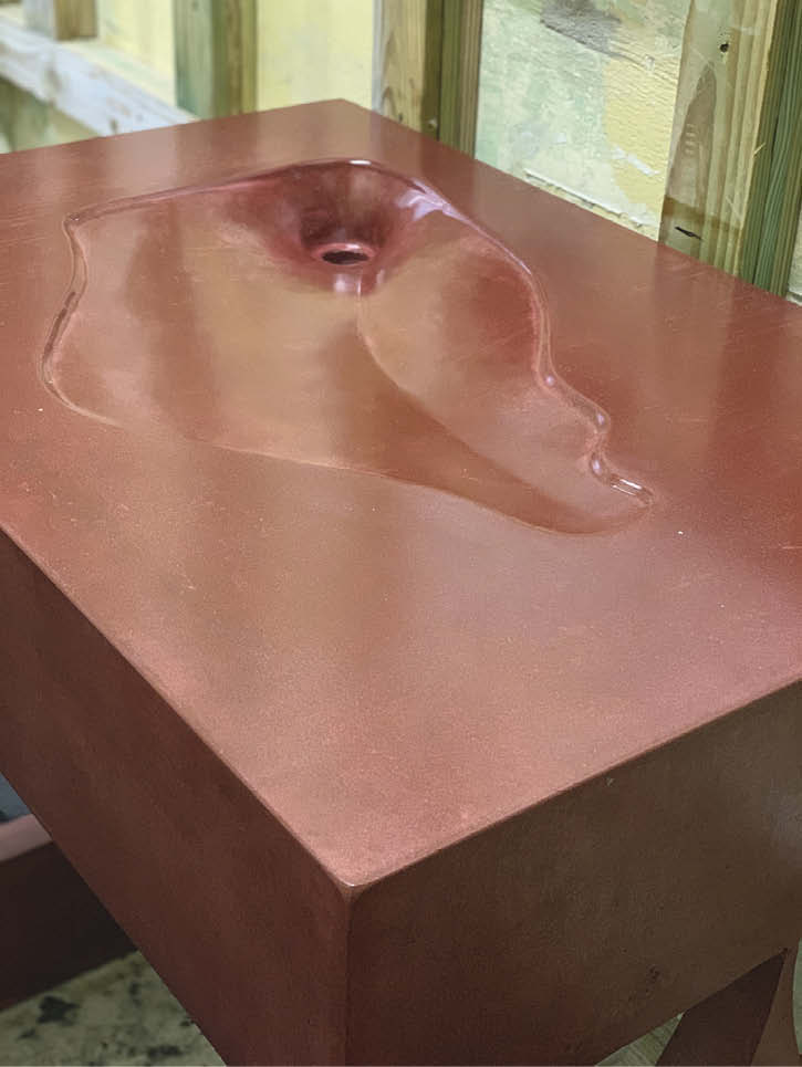 Concrete sink in red with a unique, organic shape.
