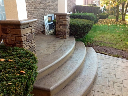 Radial steps stained in a brown color with stamped concrete leading to the first step.