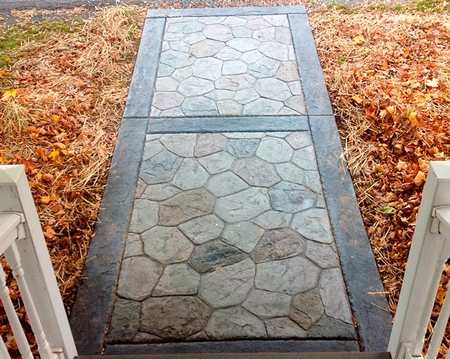 Stamped concrete walkway with cobblestone stamp pattern in alternating color stains.