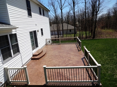 Concrete deck with a railing around it overlooking a peaceful grassy yard.