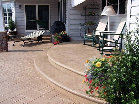 Large concrete patio with two curved steps leading into the home.