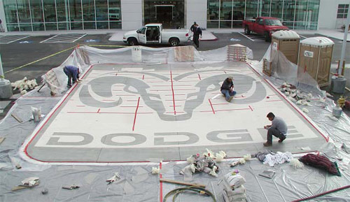 After the stencil has been adhered, computer-rendered precut material was removed, revealing the ?nal design of the Dodge logo. Panel seams and exposed edges are being covered for sandblasting, which will expose black glass aggregate in the gray concrete.