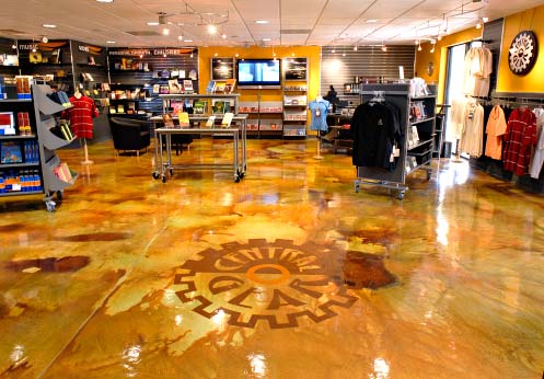 Retail application of a concrete overlay that has been colored using acid stains and then a stencil applied in a gear shape.