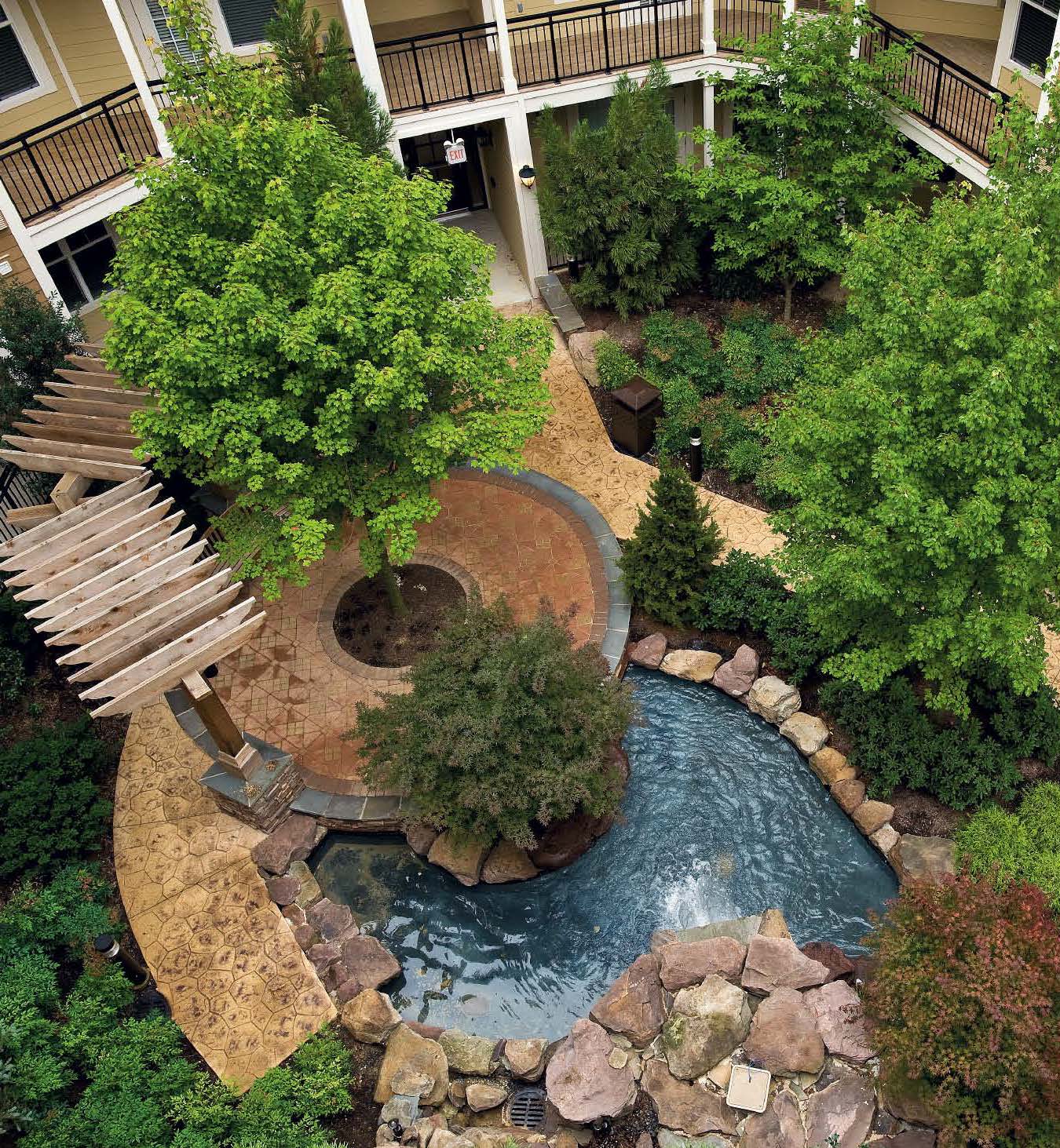 A large courtyard with greenery and concrete stamped pathways.