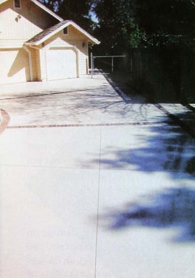 Long driveway with decorative concrete overlay covering a cracked slab. 