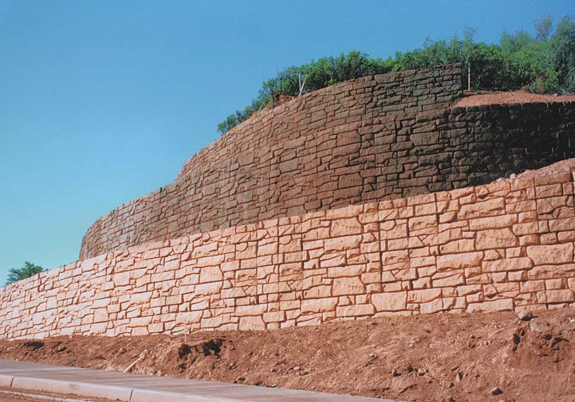 Large colored retaining wall built with formliners and colored to blend in naturally to its surrounding.