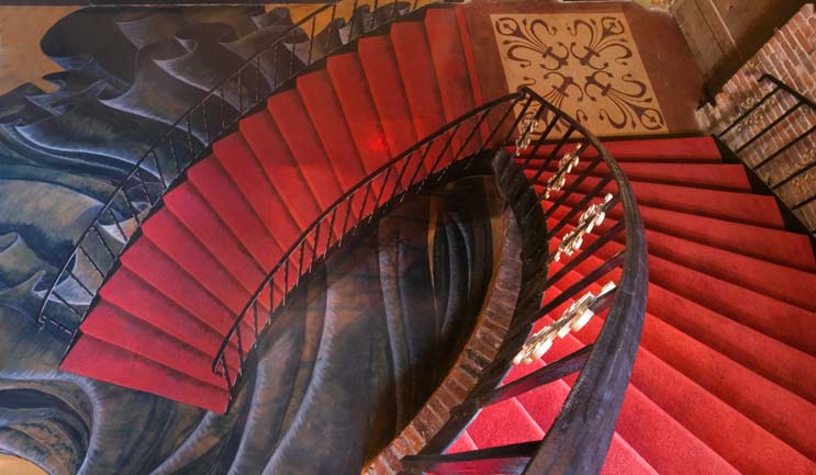 Red carpeted stair case looks to keep winding down with this 3d artwork on an overlay.