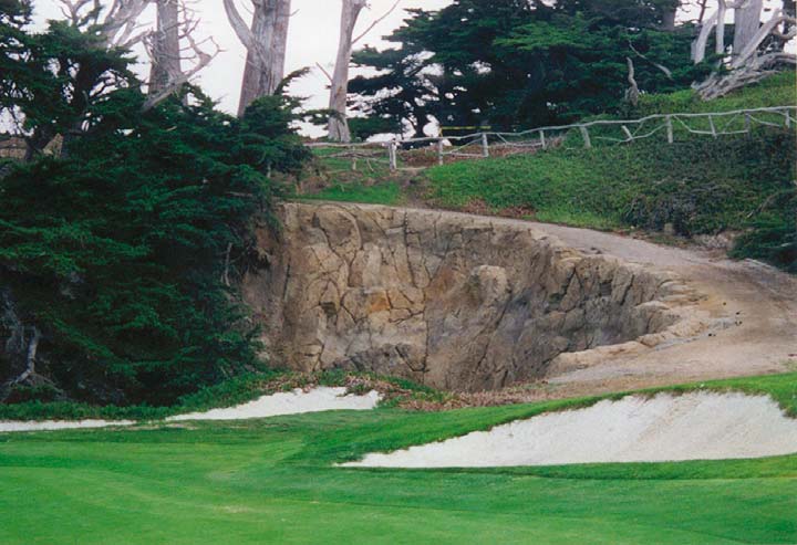 Road down a side hill with a carved concrete rock wall