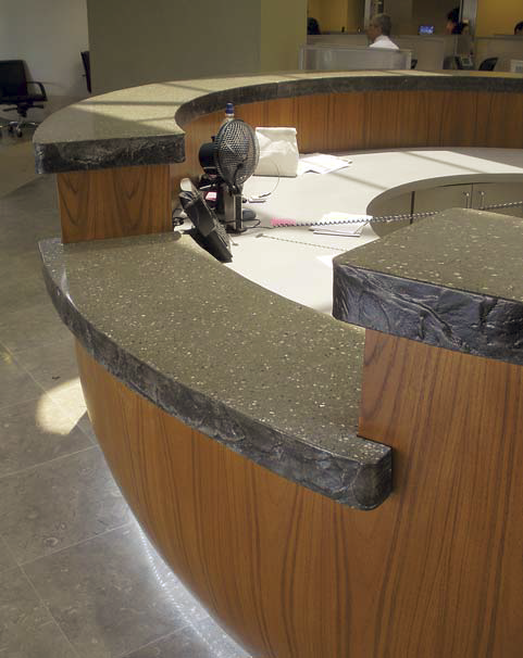 A concrete countertop flanks this reception area. The concrete is colored in charcoal with white flecks.