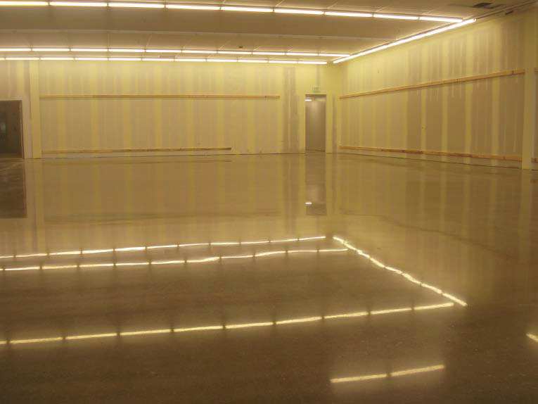 A high-gloss concrete floor that is reflecting the overhead lights.