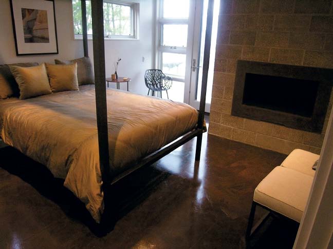 Shining concrete floor in a lovely bedroom setting with a fireplace.