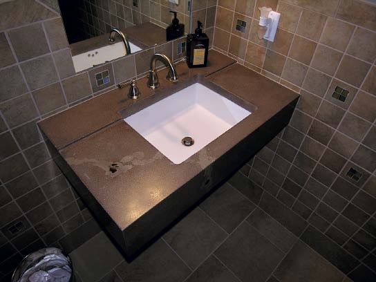 Dark gray floating concrete sink in a restroom by Troy Lemon.