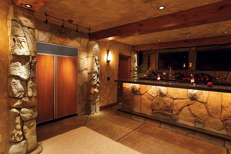 Large kitchen sporting vertical carved concrete rocks surrounding over sized refrigerator.