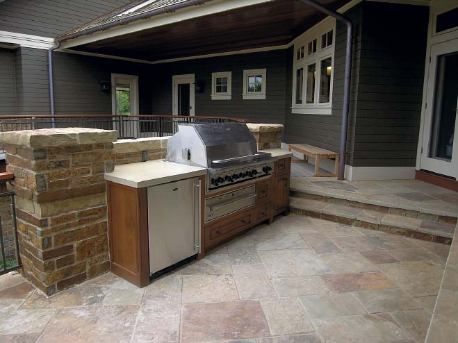 Outdoor kitchen with a BBQ surrounded by vertical concrete and concrete countertops.
