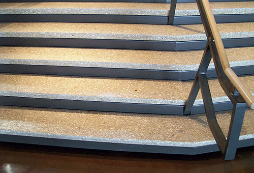 Textured two toned concrete stair case with wood and steel hand rail.