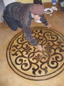 Gaye Goodman gets down to it installing a stencil onto an acid stained floor