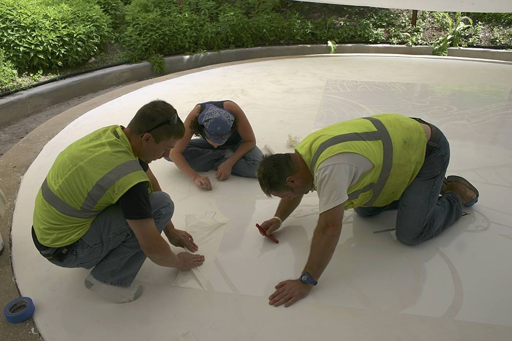 three people applying adhesive-backed vinyl stencils