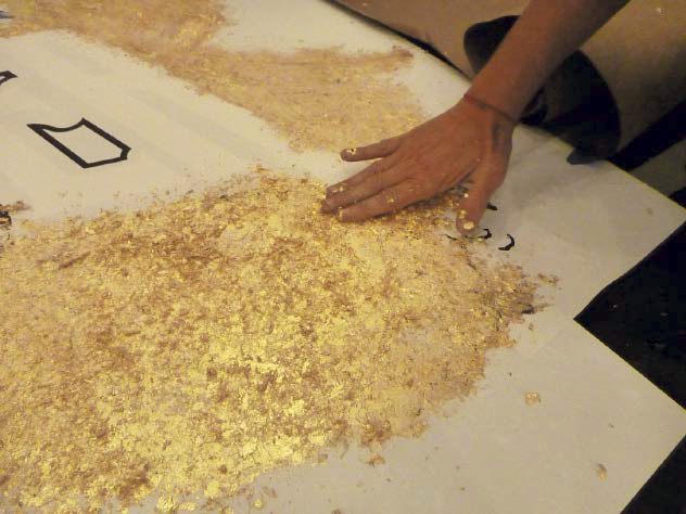 Applying the gold metallic flakes to the logo stencil.