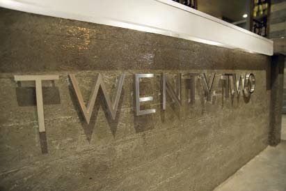 Metal letters raised off of a concrete wall that doubles as a bar lobby counter.