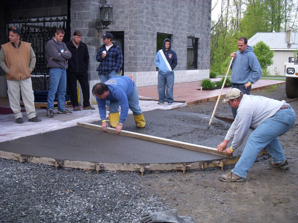 Bart Sacco and a crew screed freshly poured concrete with a piece of wood.