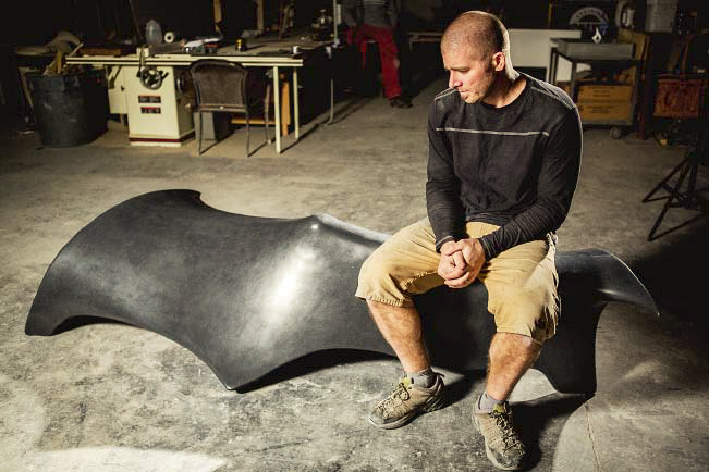 Justin Burd sits on his designed bench made with black concrete.