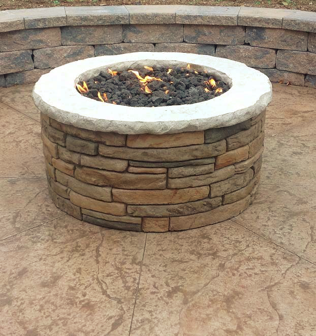 Concrete fire pit with carved concrete sitting on top of stamped concrete.