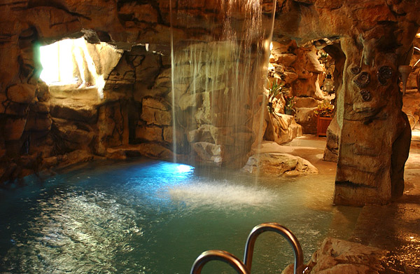 Artificial Rock Waterfall inside a huge faux rock structure cascading into a swimming pool.
