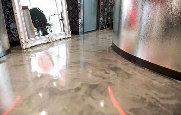 Metallic epoxy concrete floor in a swirling white and platinum grace this busy floor