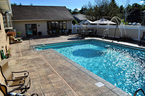 The pool deck consisted of a concrete coping around the pool, surrounded by pavers. Originally, the homeowner had sought estimates on tearing out the concrete, taking up the pavers and reusing the pavers in a new deck.