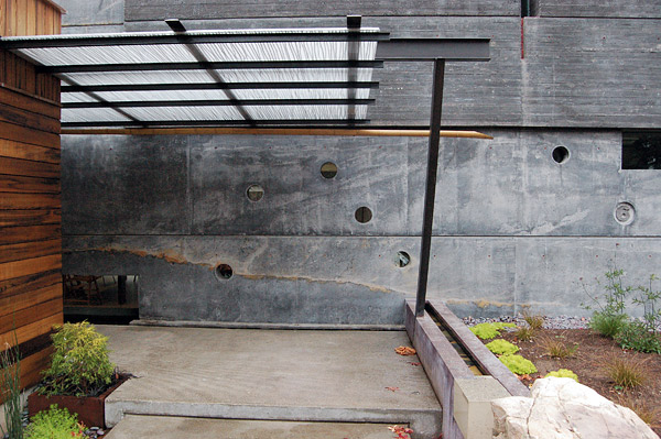 In addition to integrally colored concrete, FuTung Chengs House 6 (note the 6 at the far right) in Menlo Park, California, features a water sluice on the right. Water runs toward the homes wall and drops over the edge into a channel running left and into a pond. The entrys canopy is made of carbonate embedded with twigs. The assembled elements reflect Chengs design philosophy of integrating architectural and structural elements. Photo by Matthew Millman Photography