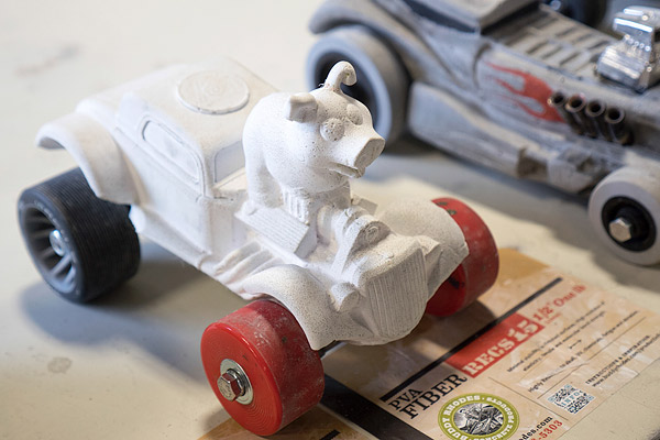 concrete derby car with a pig in an old hot rod car