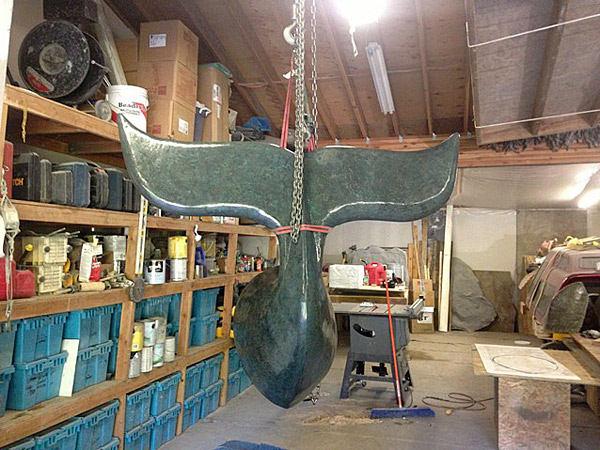 Whales Tail Bench made of concrete hanging from a rope in a garage.