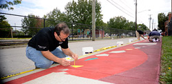man painting sidewalk concrete mosaic