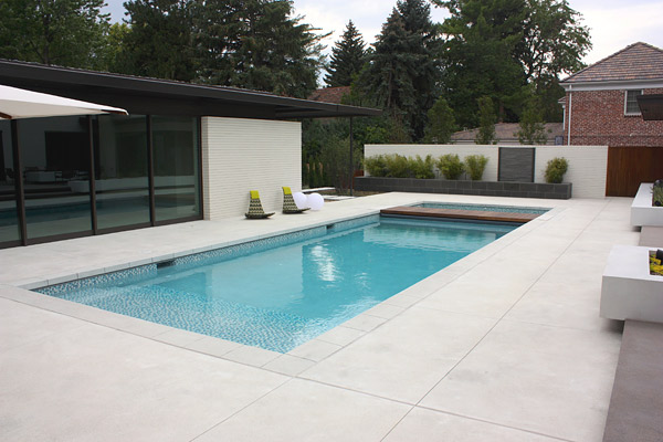 Rectangle luxurious pool with cool chairs, white concrete pool balls, concrete with a smooth, brushed finish, one awesome pool deck