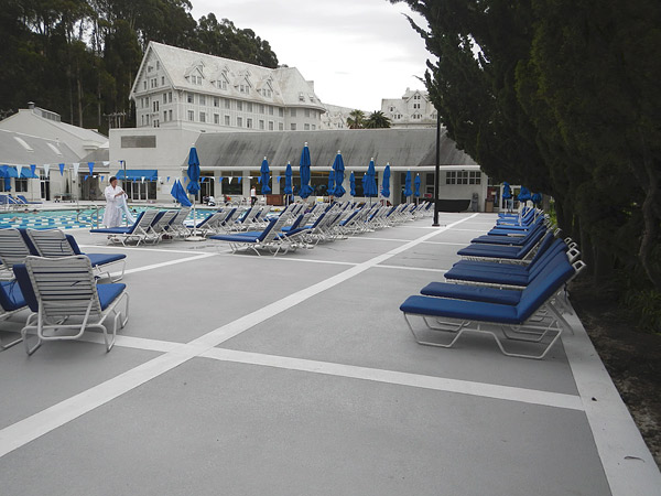concrete pool deck with blue chairs