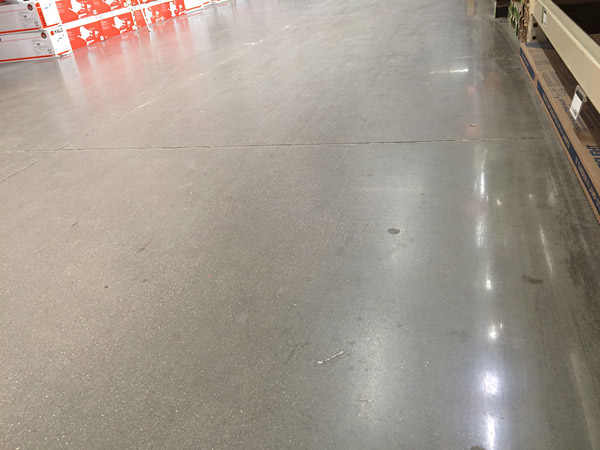 concrete sealer wearing off of polished concrete floor in a huge box store's aisle.