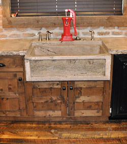 Red hand pump as the kitchen faucet over a concrete sink.