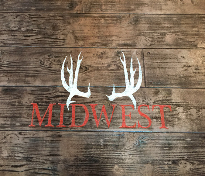 midwest horn logo engraved into a wood plank look concrete floor.